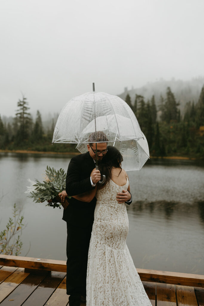Bride and groom standing on a misty dock surrounded by evergreens during their intimate elopement.