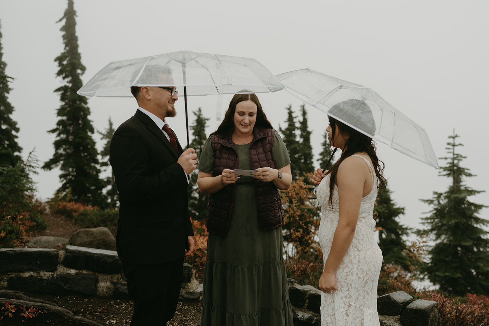 Couple exchanging vows under umbrellas during their rainy wedding ceremony at Mount Baker.