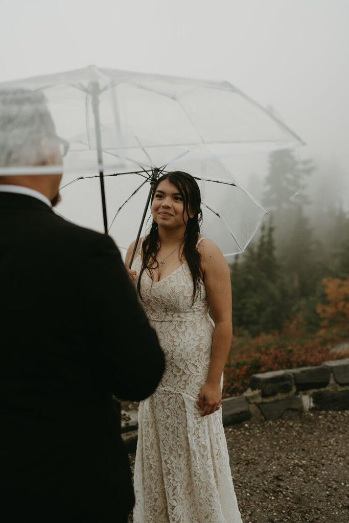 Bride looking at her partner with a soft smile during their misty mountain ceremony.