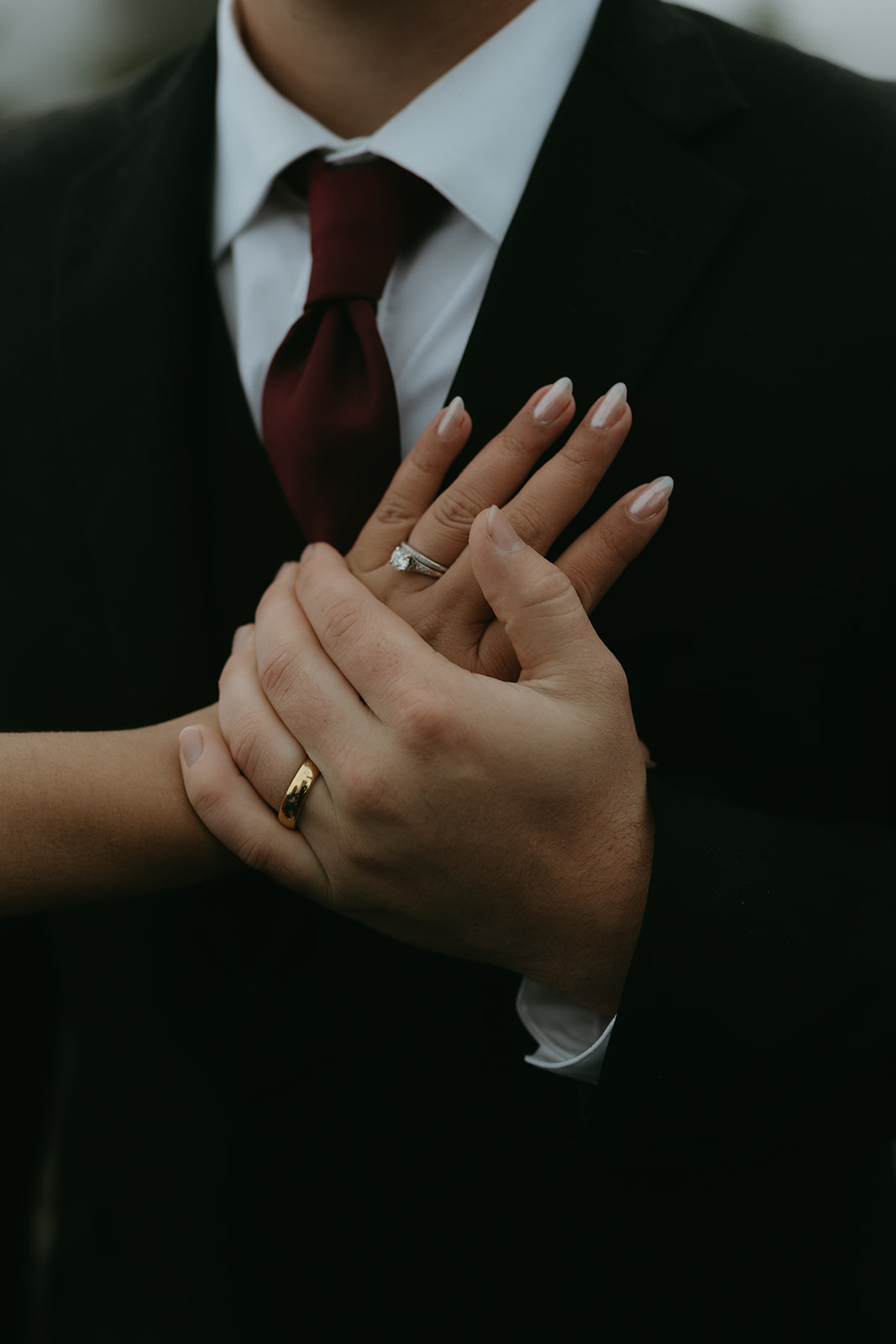 Close-up of hands gently held, showcasing wedding rings and emotional connection.