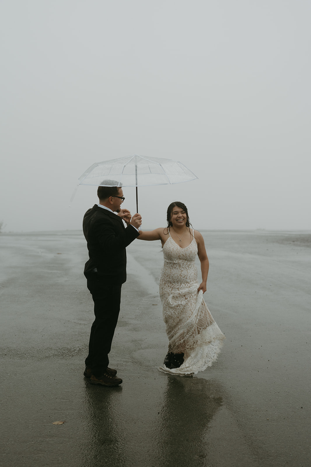 Bride and groom sharing a joyful moment while walking together during their rainy wedding.