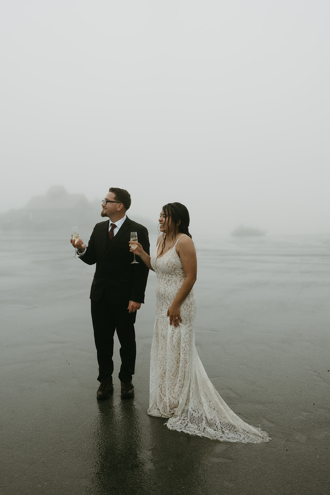 Bride and groom sharing a quiet toast together in the mist after their rainy wedding ceremony.