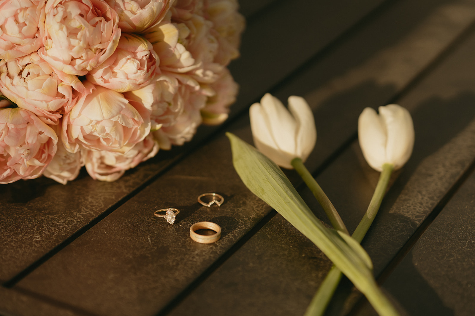 Flat lay of wedding rings, pale tulips, and a blush peony bouquet captured during a Whidbey Island wedding.