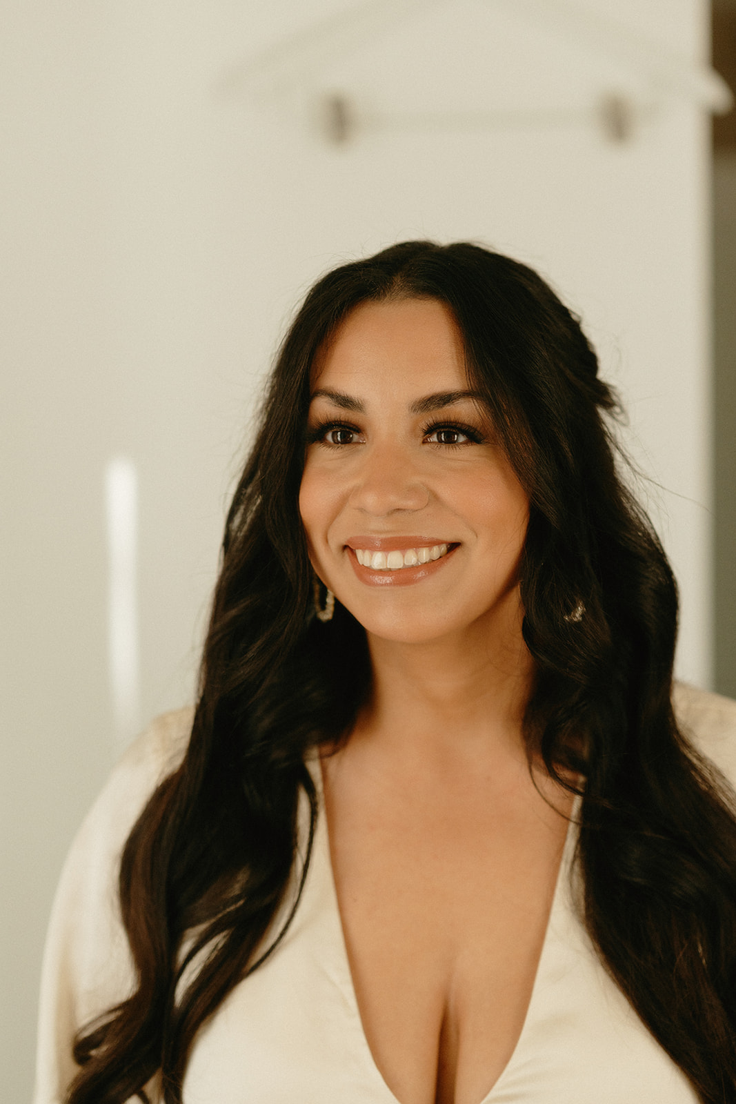 Close-up of the bride smiling, her long hair styled in loose waves and soft natural makeup.