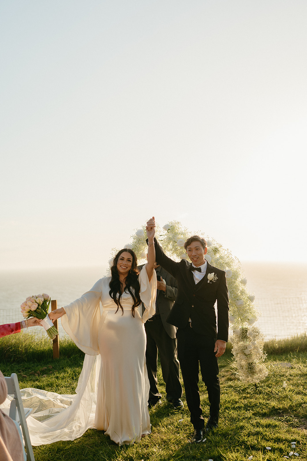 Newlyweds celebrating with raised hands and joyful smiles just after their ceremony.