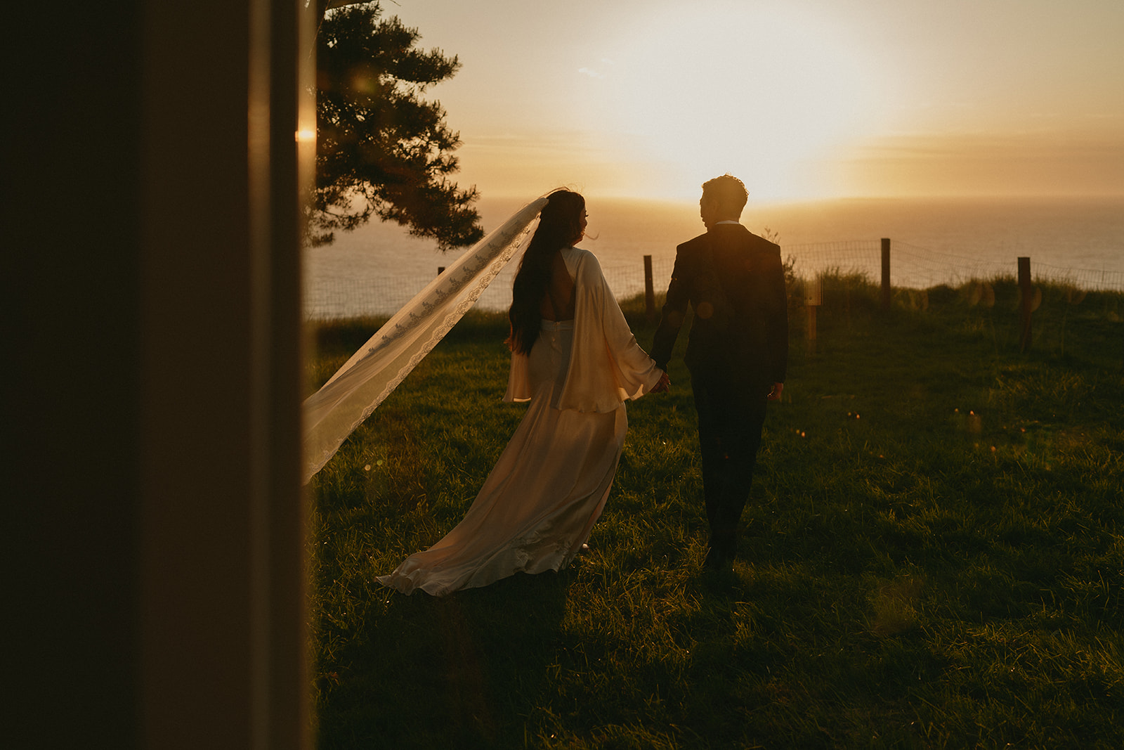 Romantic Whidbey Island wedding moment as the couple walks into golden hour, veil trailing behind. 