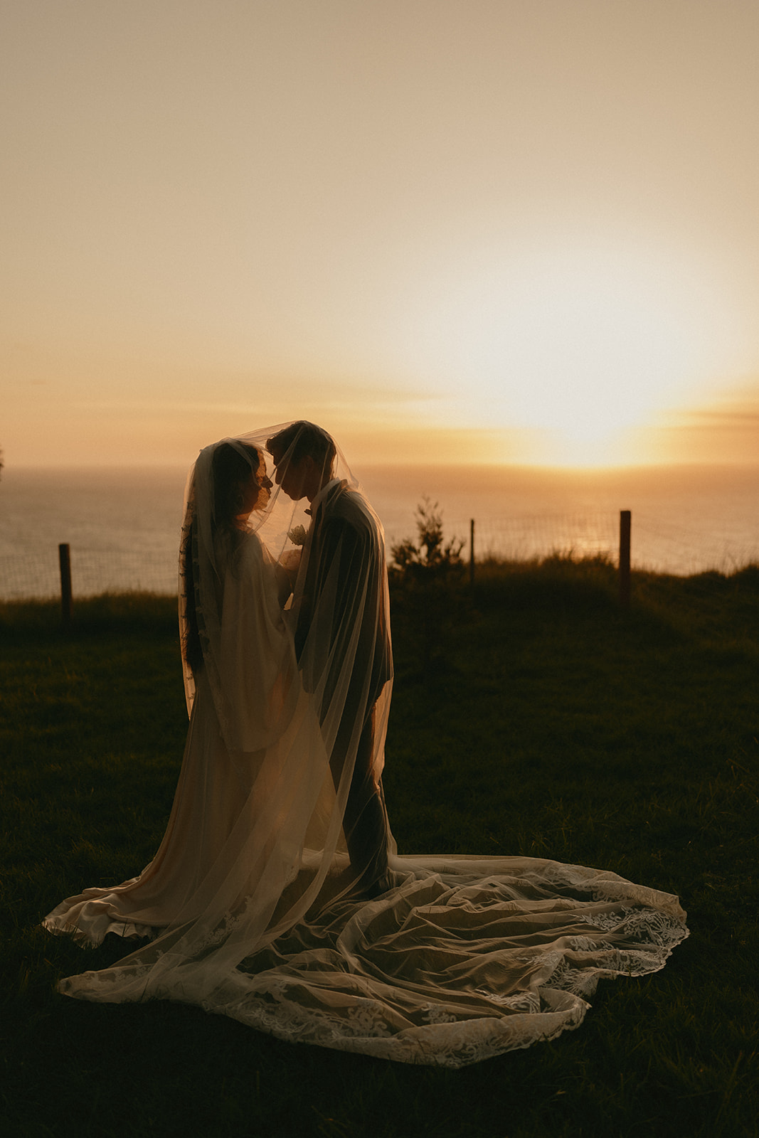 Bride and groom sharing a quiet moment under the veil, framed by golden sunset light on Whidbey Island.