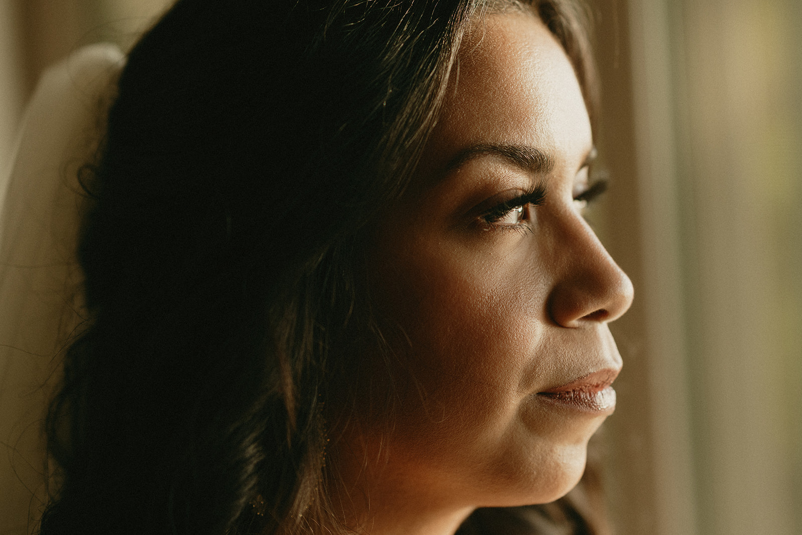 Close-up bridal portrait capturing a soft, emotional expression near the window.
