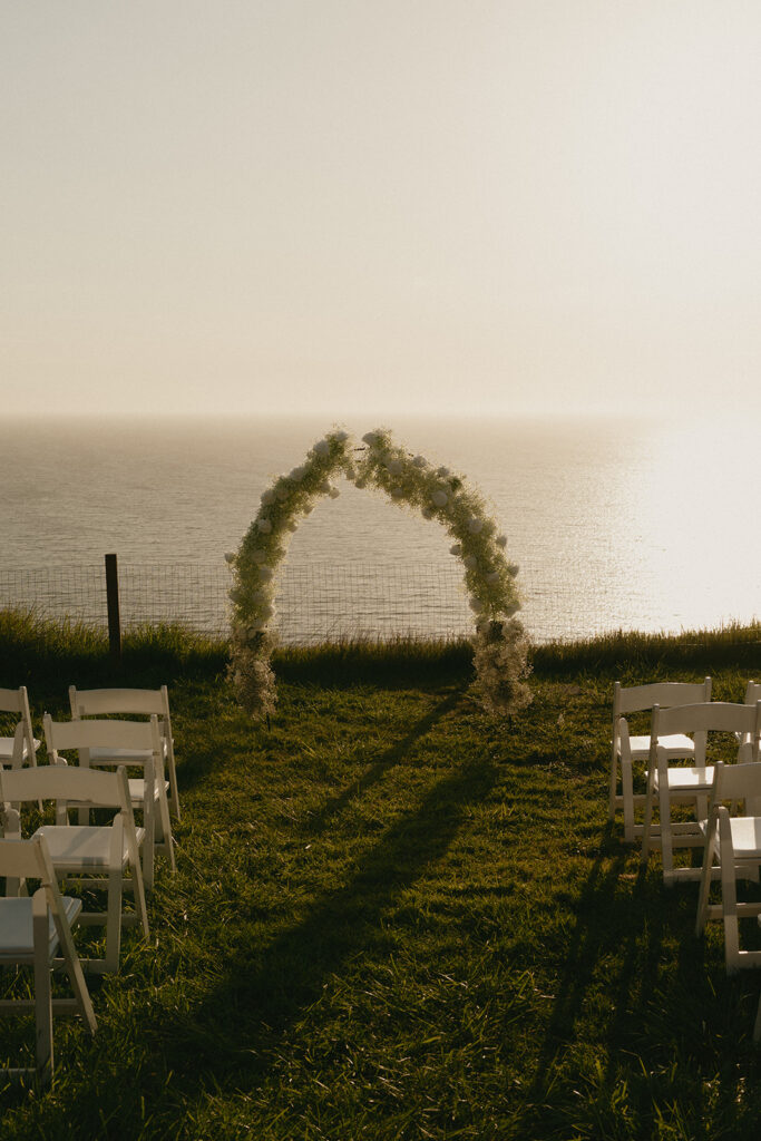 Ceremony setup with white chairs and a floral arch facing the ocean during a Whidbey Island wedding.