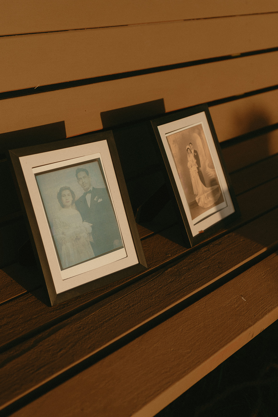 Vintage wedding portraits framed and displayed on a bench as part of the couple’s decor.