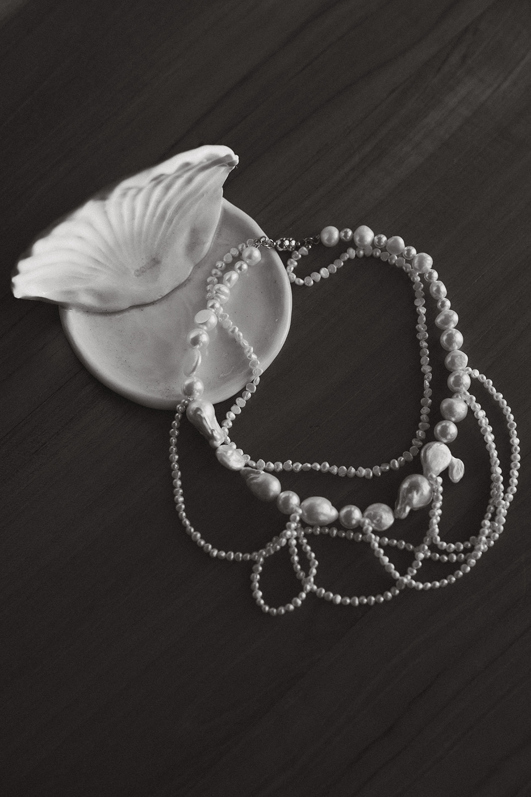 A still life of layered pearl necklaces resting in a ceramic shell dish—elegant, simple, and quietly symbolic.