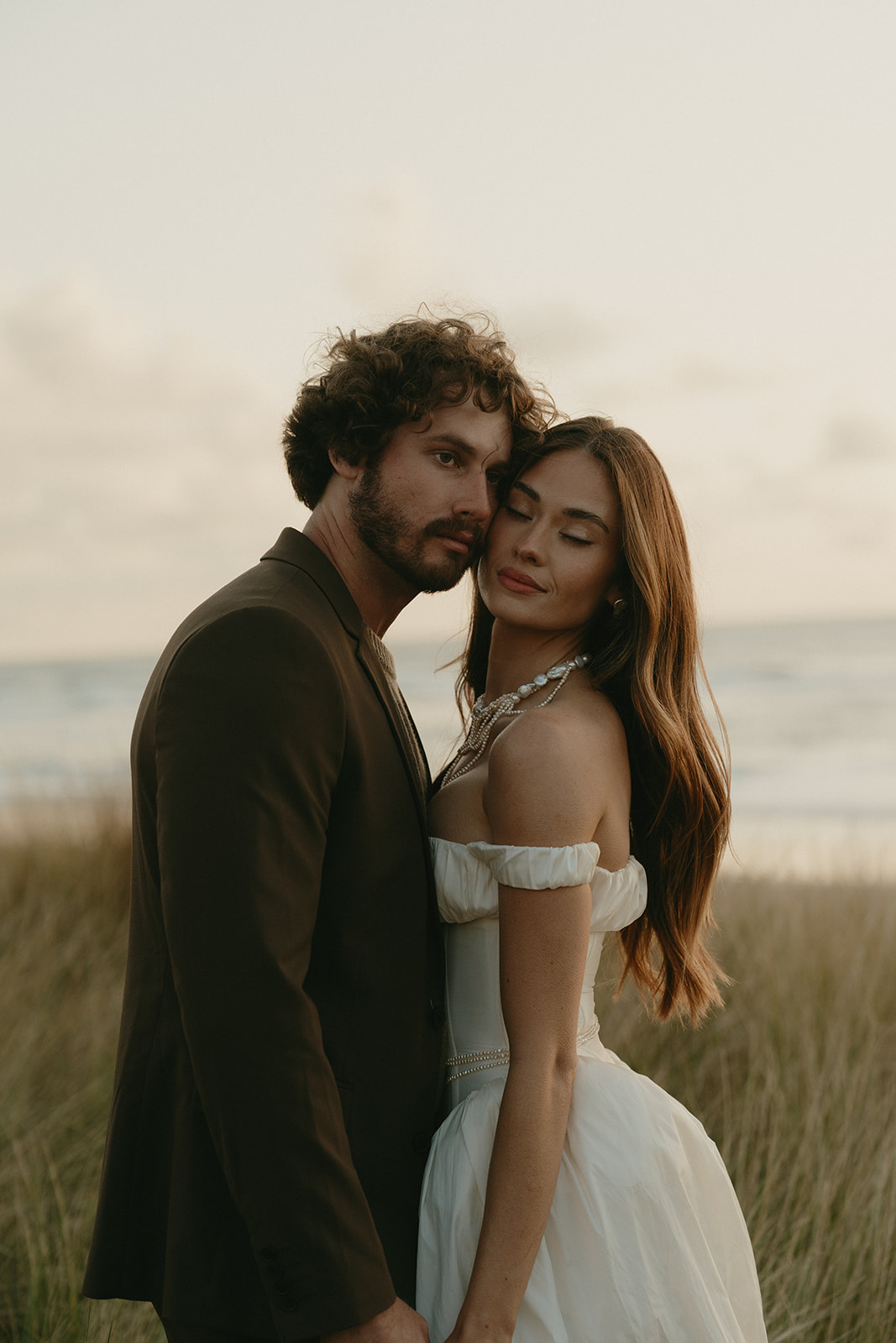 Close-up of bride and groom embracing softly at the edge of the beach, captured during their Oregon Coast elopement.