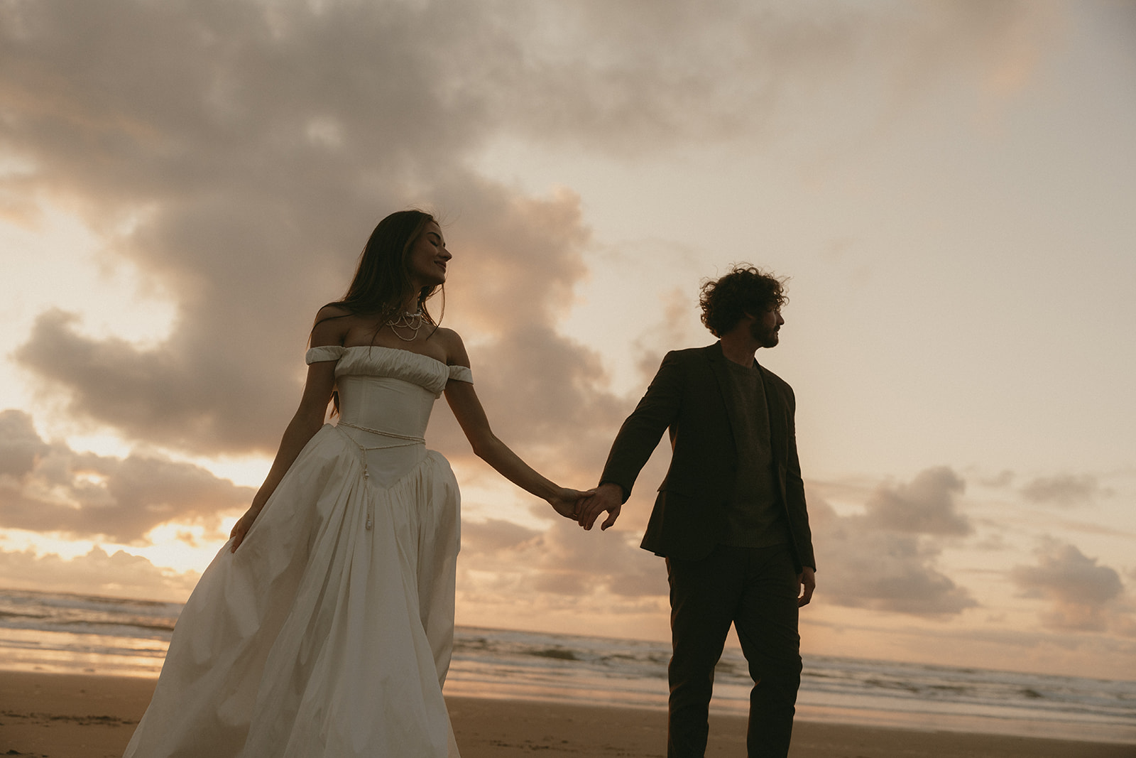 Hand in hand, the couple walks along the beach as the sky begins to fade, the bride’s peaceful smile mirroring the calm of the ocean breeze.