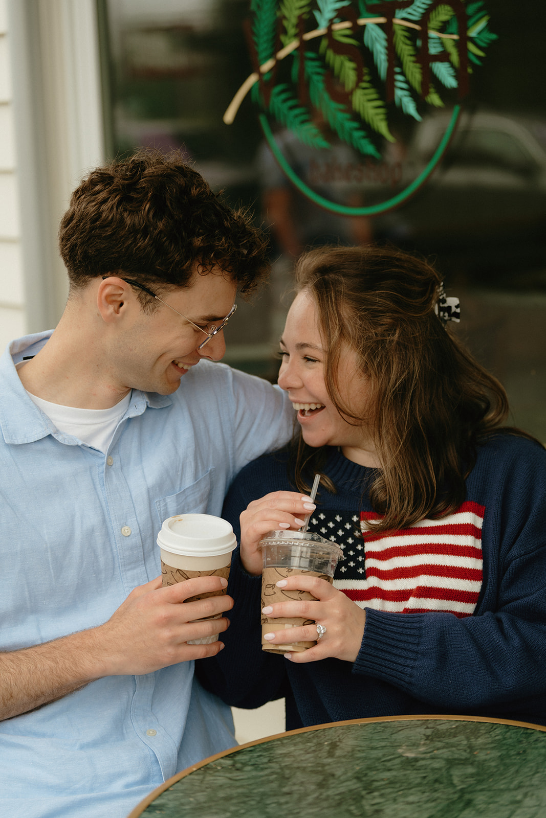 Couple sharing a cozy coffee moment outside a local café, smiles full of connection and joy.