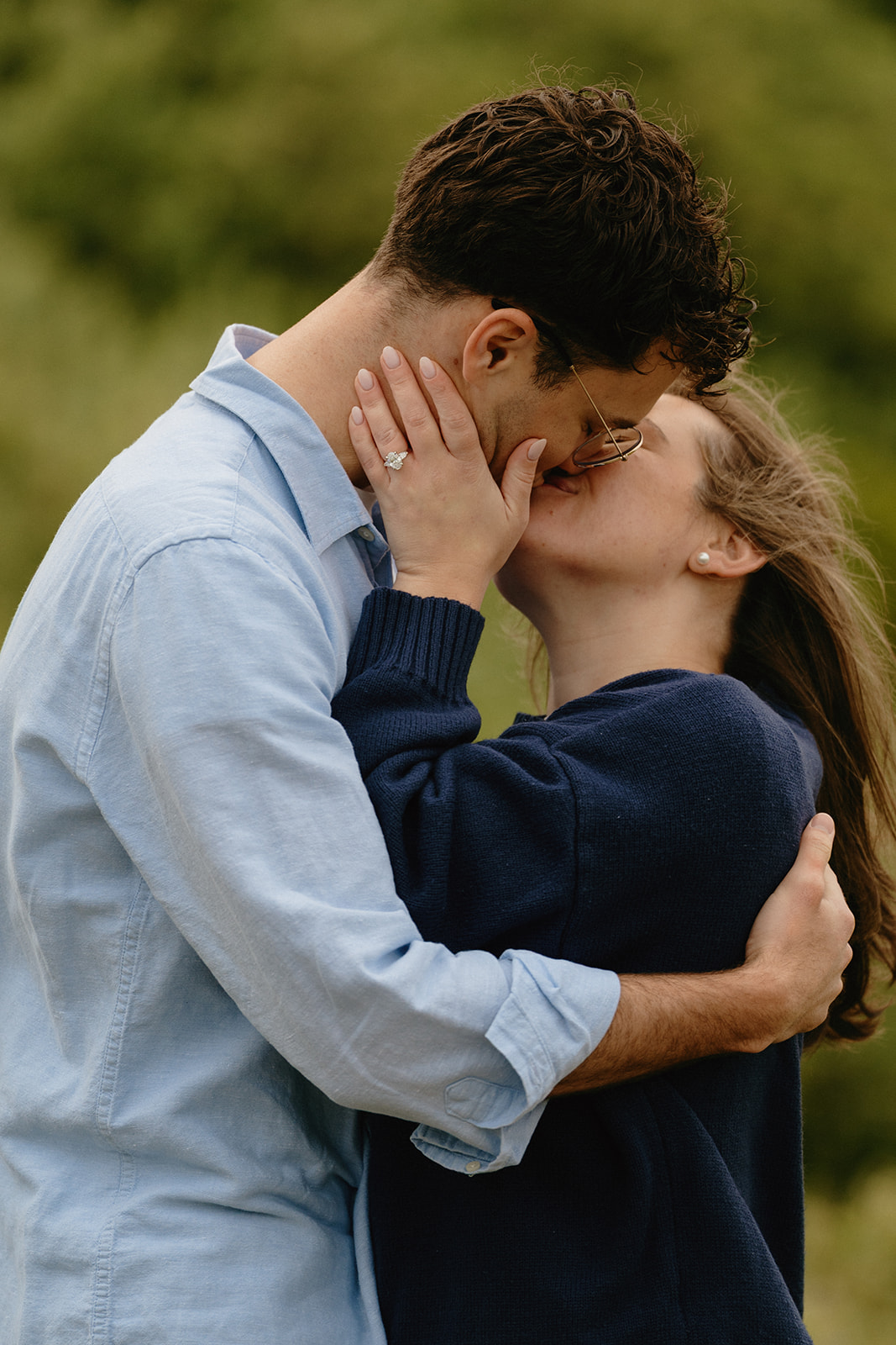 Close-up of a couple kissing, the engagement ring softly visible, highlighting love and connection.
