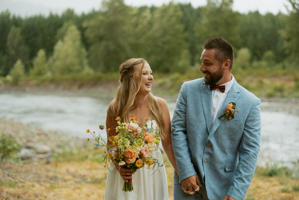 Couple walking and laughing together during light rain during intimate elopement
