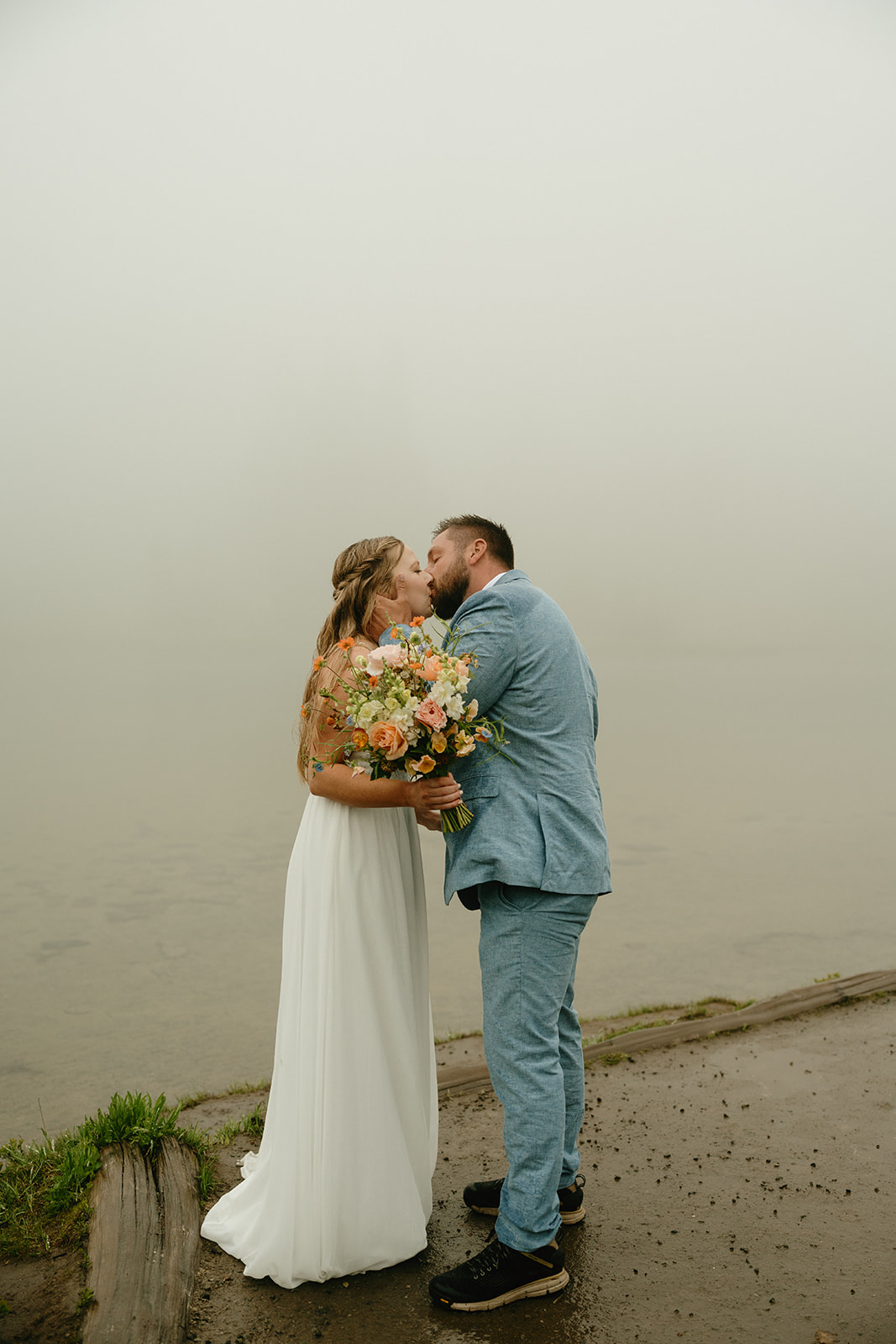 Bride and groom kiss on dock after private elopement ceremony in Mount Rainier National Park