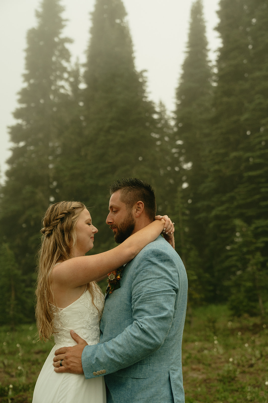 Couple embracing in the fog, taking a quiet moment surrounded by trees and soft morning light.