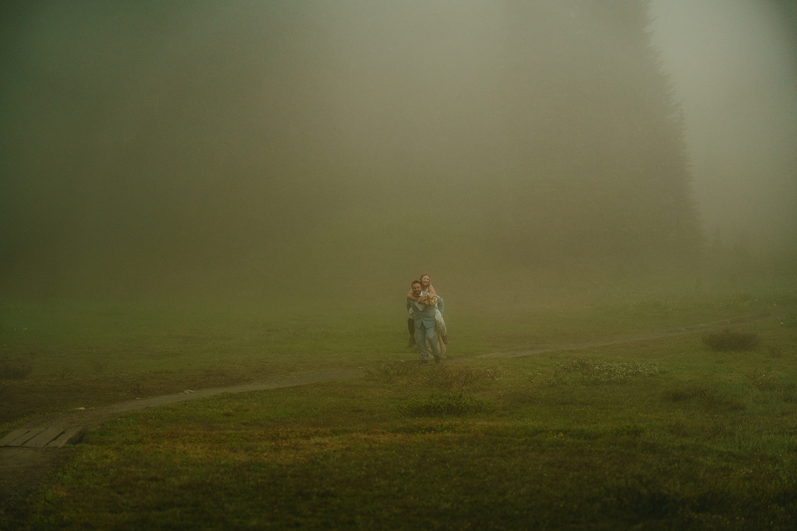 Elopement couple walking through an open meadow wrapped in fog, surrounded by quiet stillness in Mount Rainier National Park.