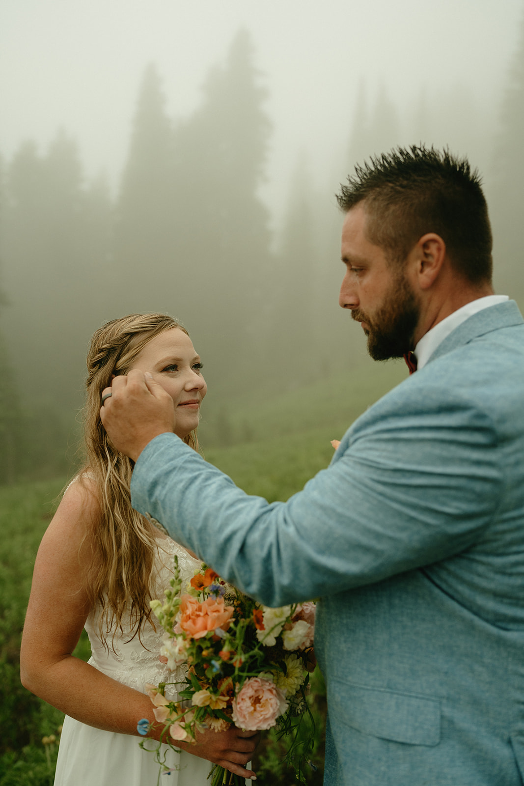 Groom brushing the bride’s hair away from her face during an intimate moment in Mount Rainier National Park.