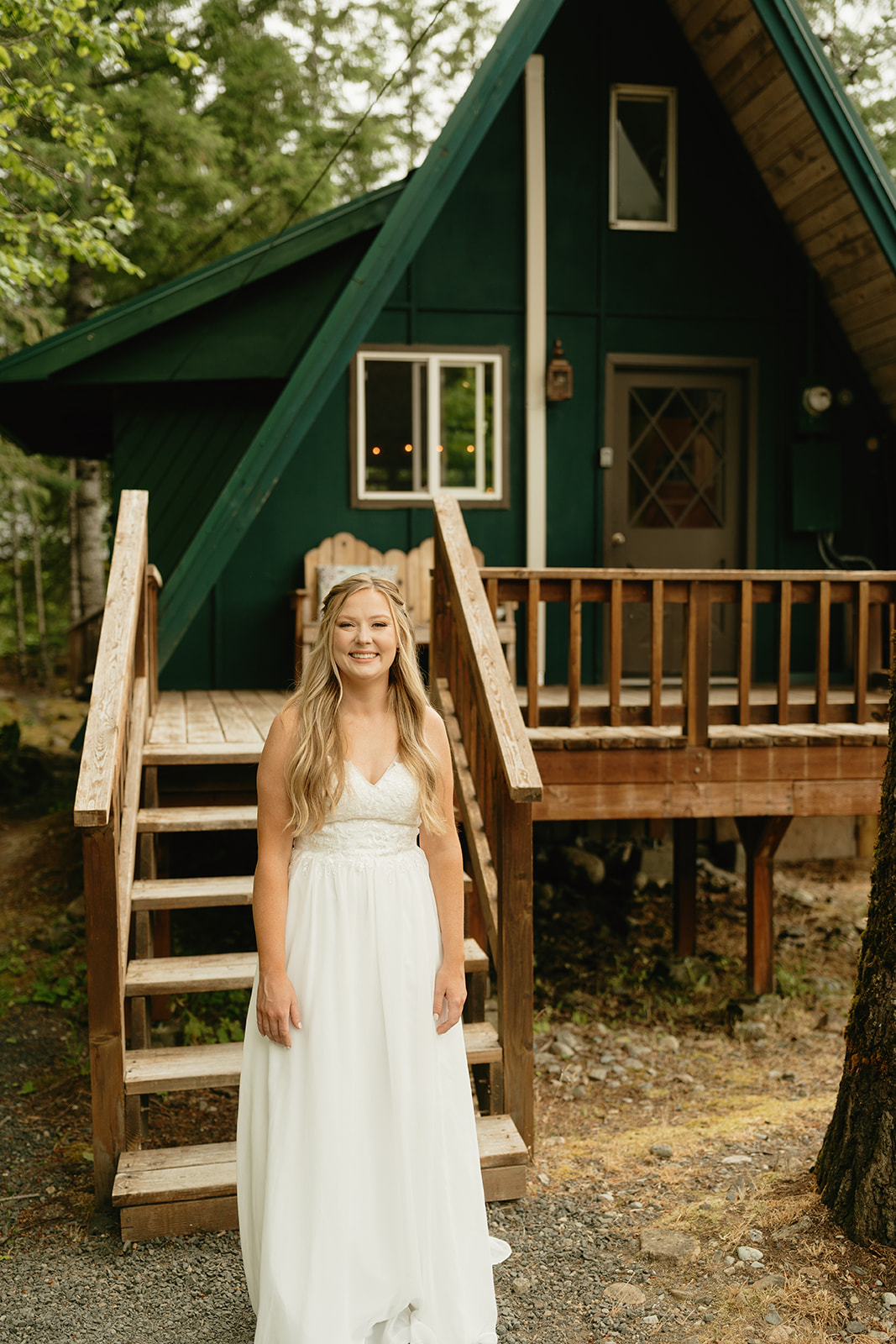 Bride wearing lace wedding gown smiling as she walks down stairs of a-frame cabin