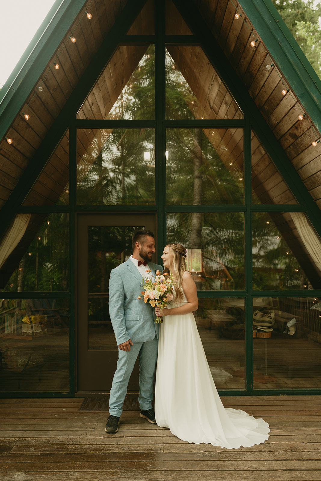 Couple standing in front of a cozy A-frame cabin, sharing a quiet moment before their elopement day begins.