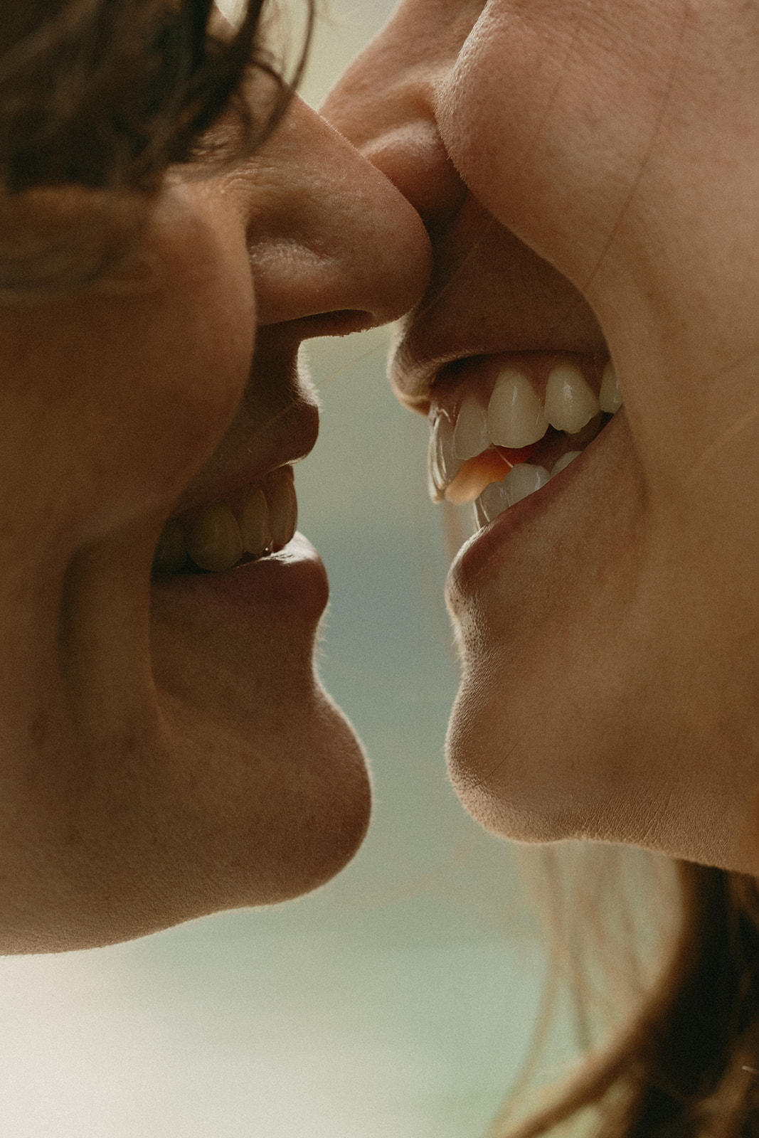 A close-up of two smiling faces about to kiss, their noses nearly touching, capturing an unspoken moment of joy and tenderness.