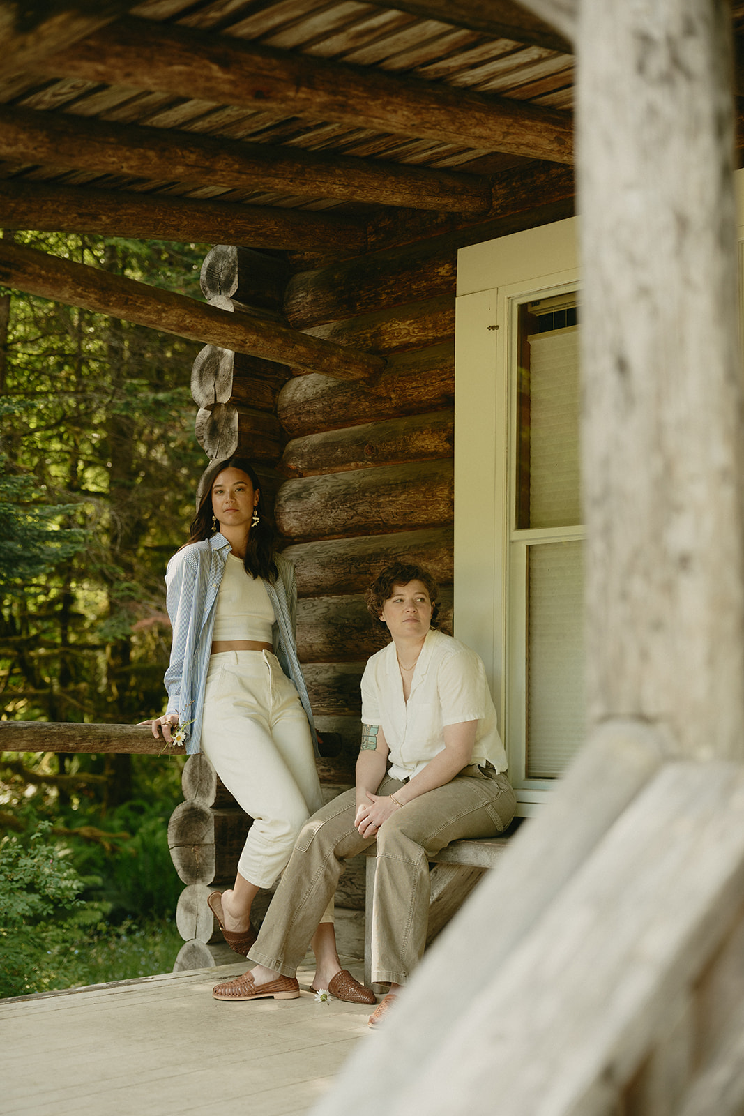 Sitting quietly on a rustic cabin porch, a couple leans into the peaceful forest around them.