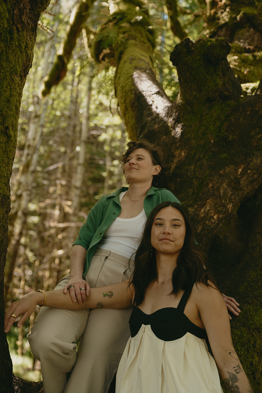 A couple leans gently into one another beneath the limbs of an old mossy tree, grounded in stillness and trust.