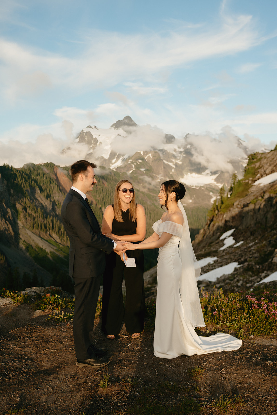 A couple exchanges vows with their officiant in view of snow-capped peaks while eloping in Washington.