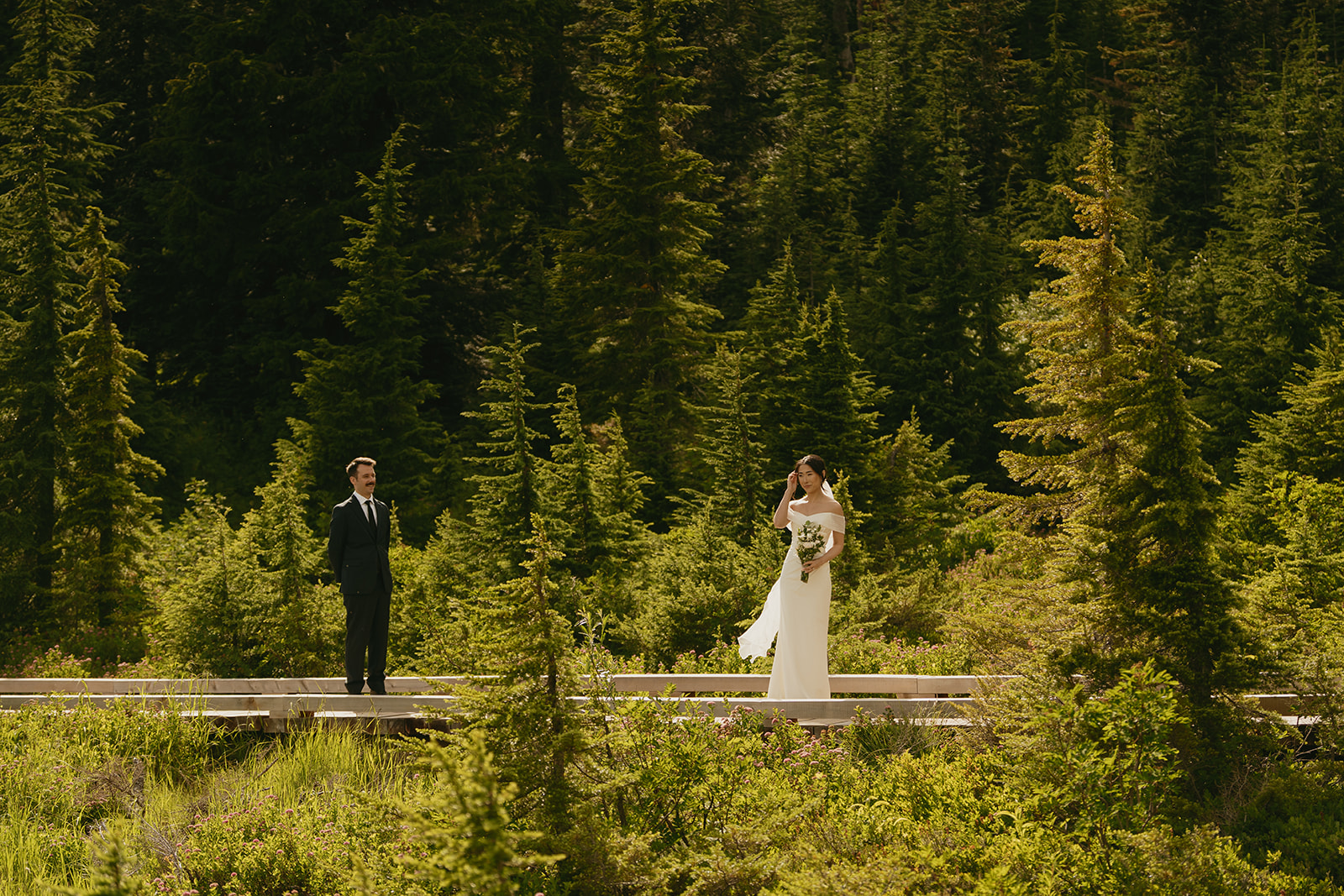 A couple shares a first look moment among tall pines while eloping in Washington.