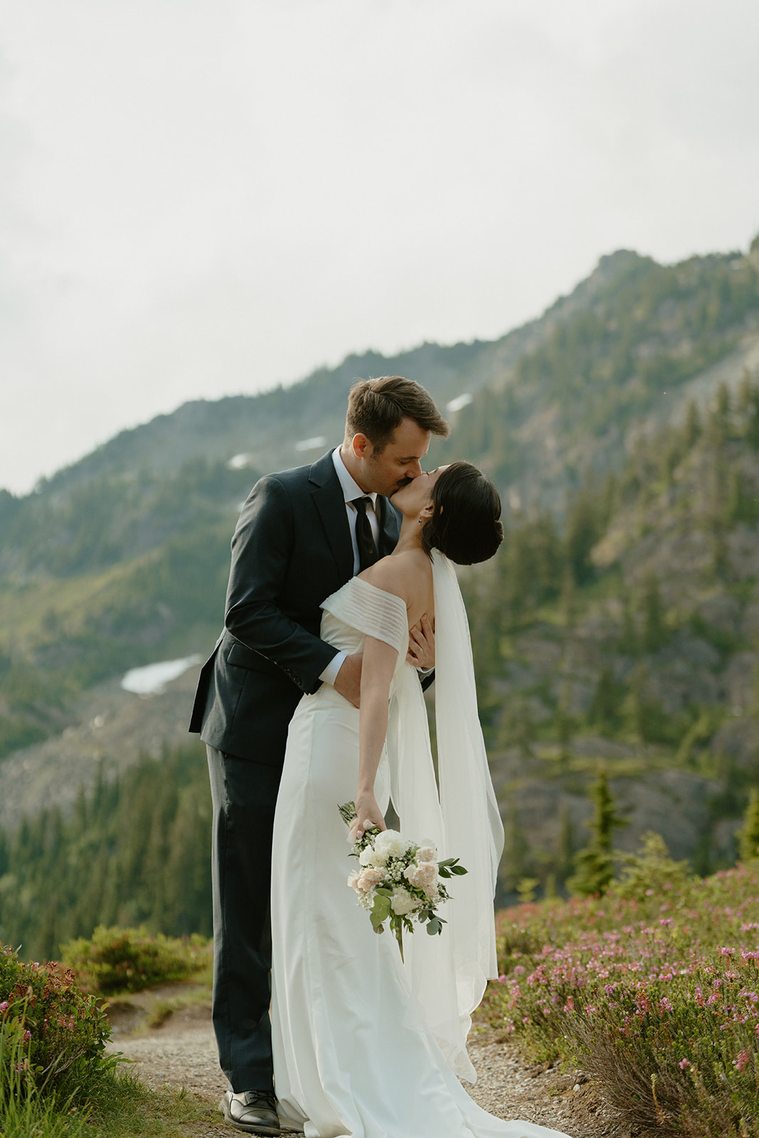 Groom dips his bride for a kiss on a wildflower-lined trail while eloping in Washington.