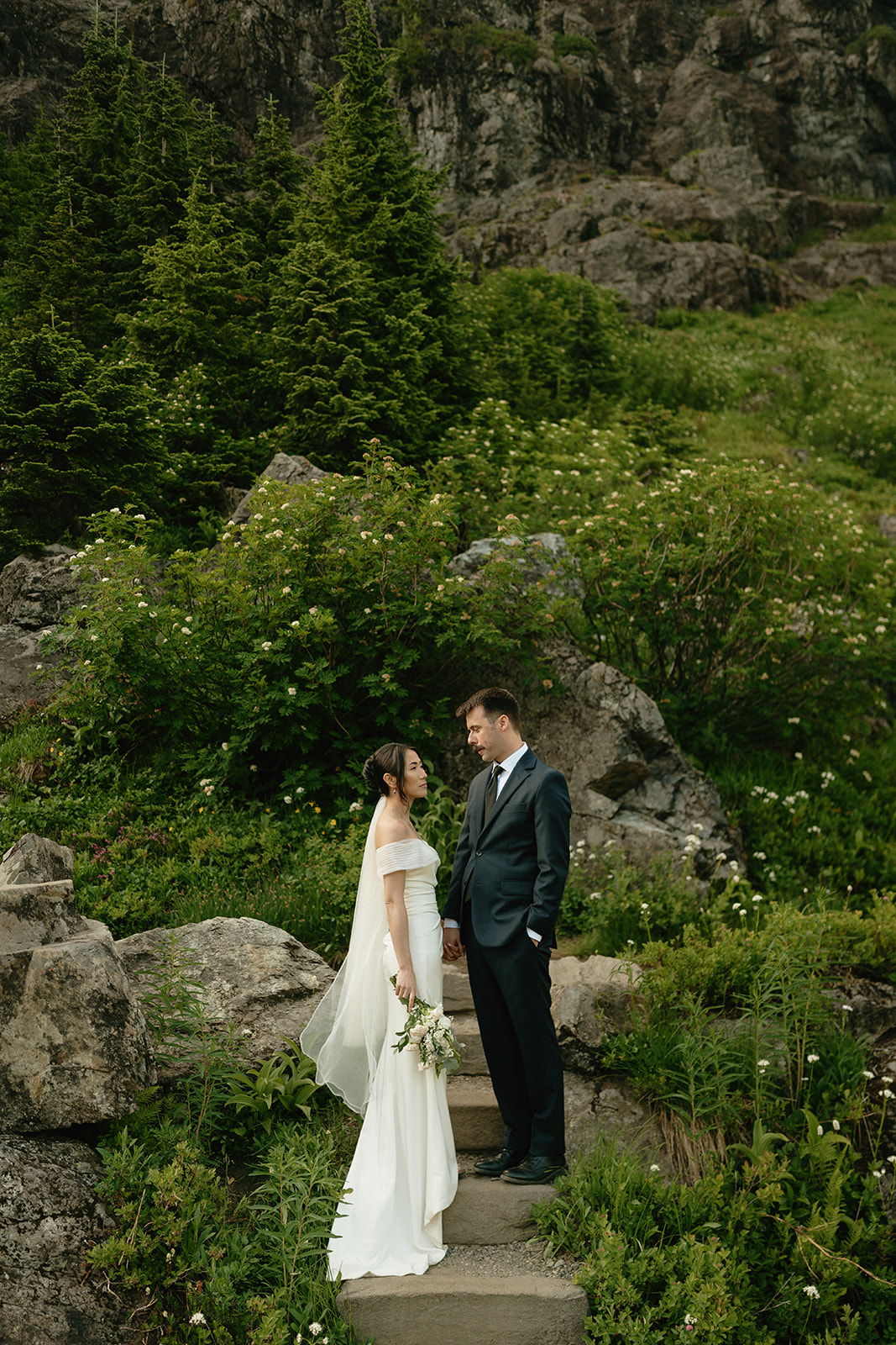 Intimate moment between a couple standing on stone steps surrounded by greenery.
