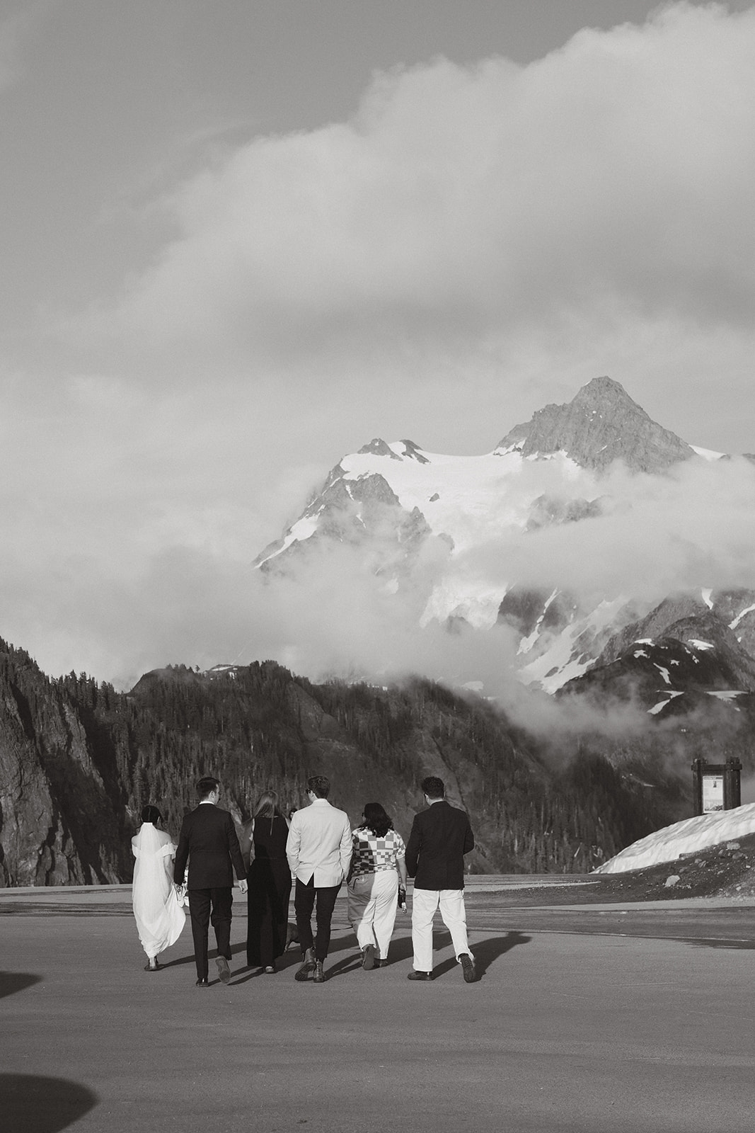 A small group walks toward snow-covered peaks for a mountaintop ceremony.