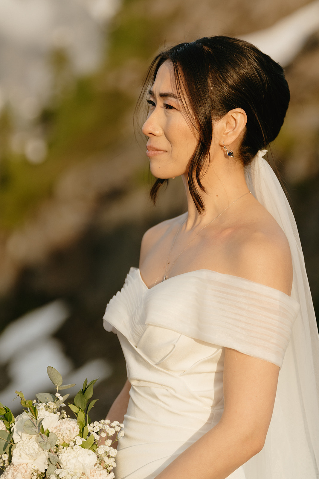 Portrait of a bride holding white flowers, softly lit in the golden light of a Washington mountain evening.