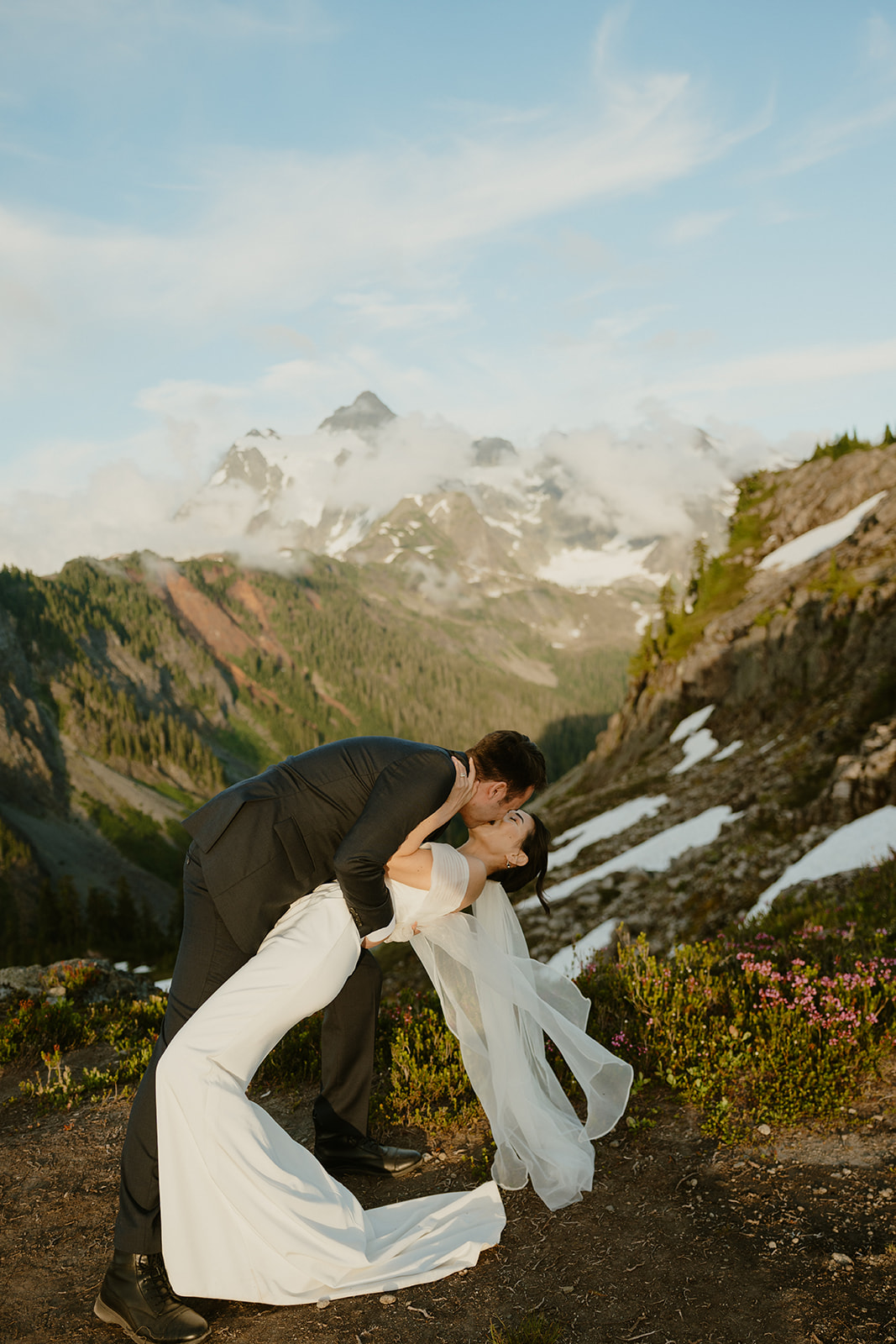 Groom dips the bride for a kiss beneath snow-capped peaks, a joyful moment of eloping in Washington.