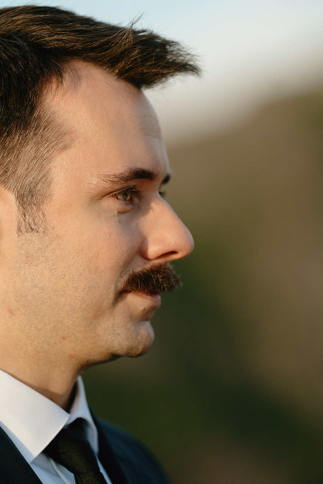 Close-up portrait of the groom, quietly listening during their mountain ceremony.