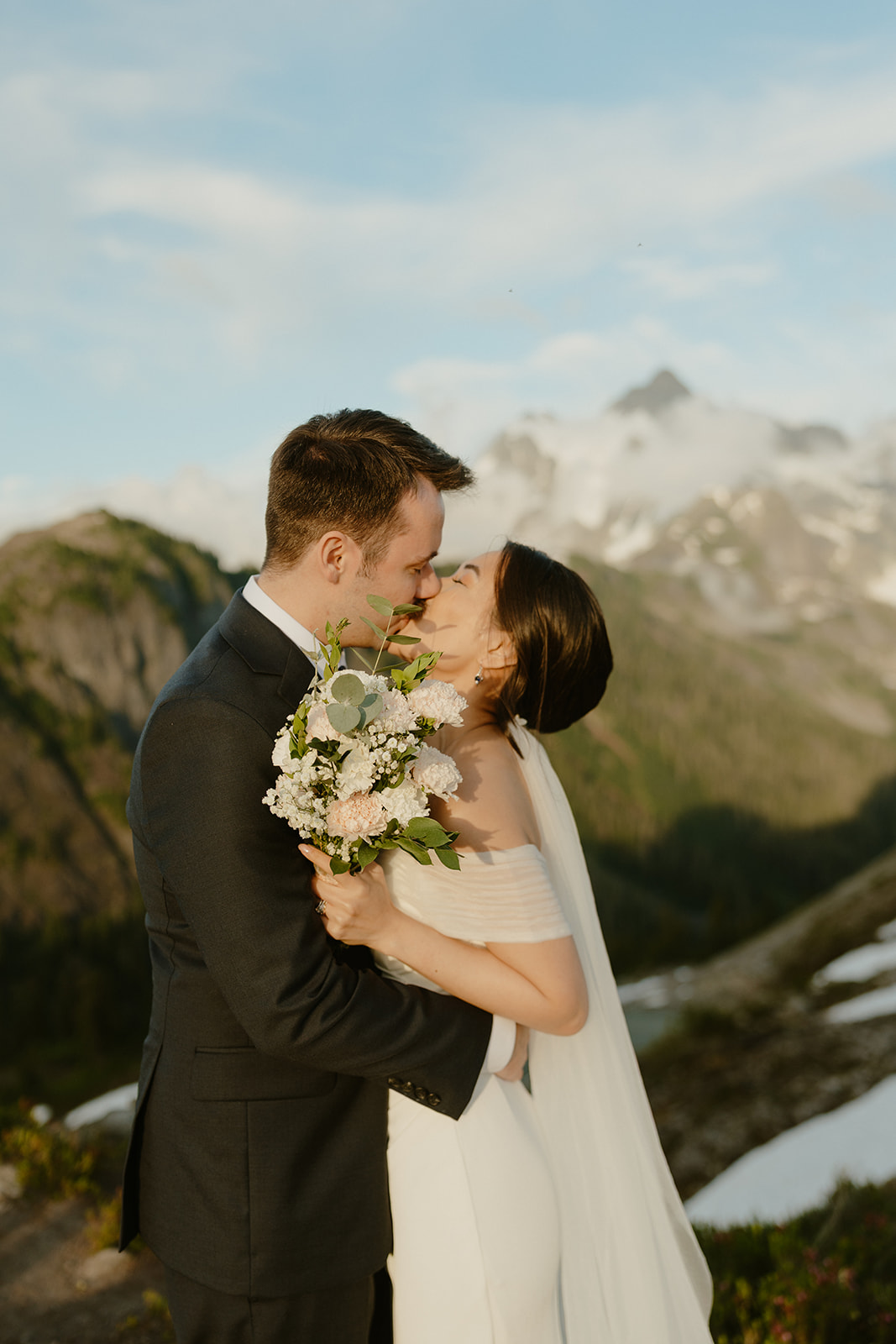 Eloping in Washington, the couple shares a kiss with snow-capped peaks behind them.