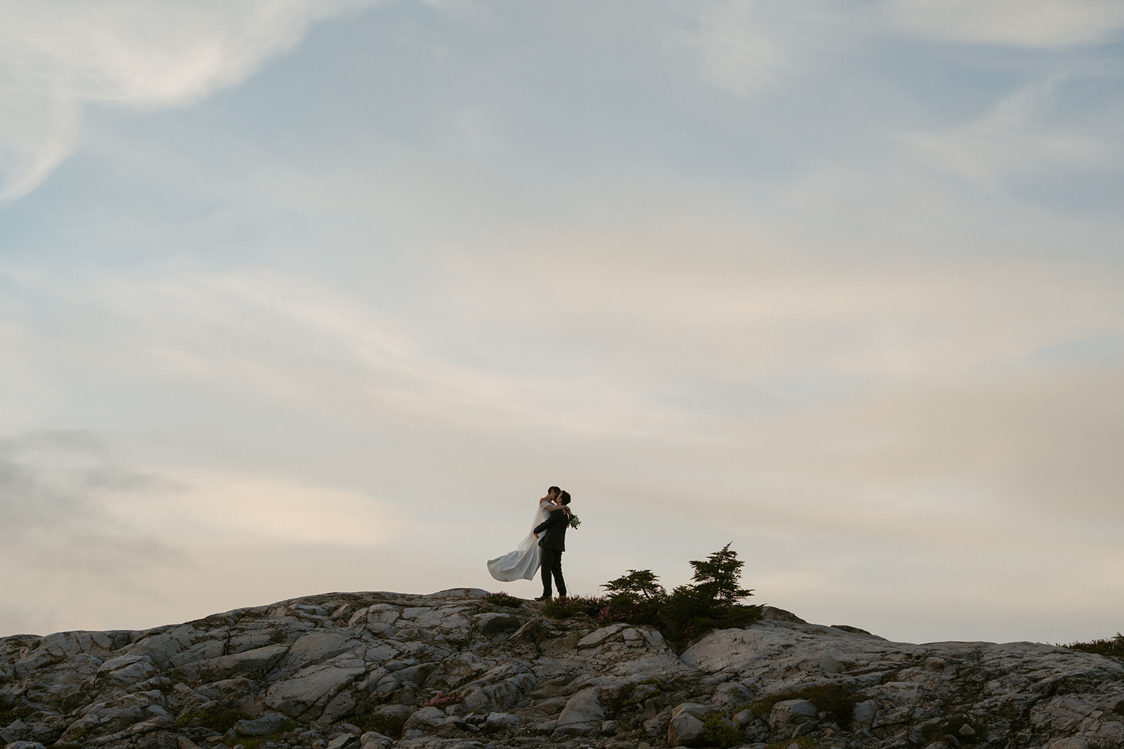 Newlyweds embrace under a pastel sky while eloping in Washington’s alpine wilderness.