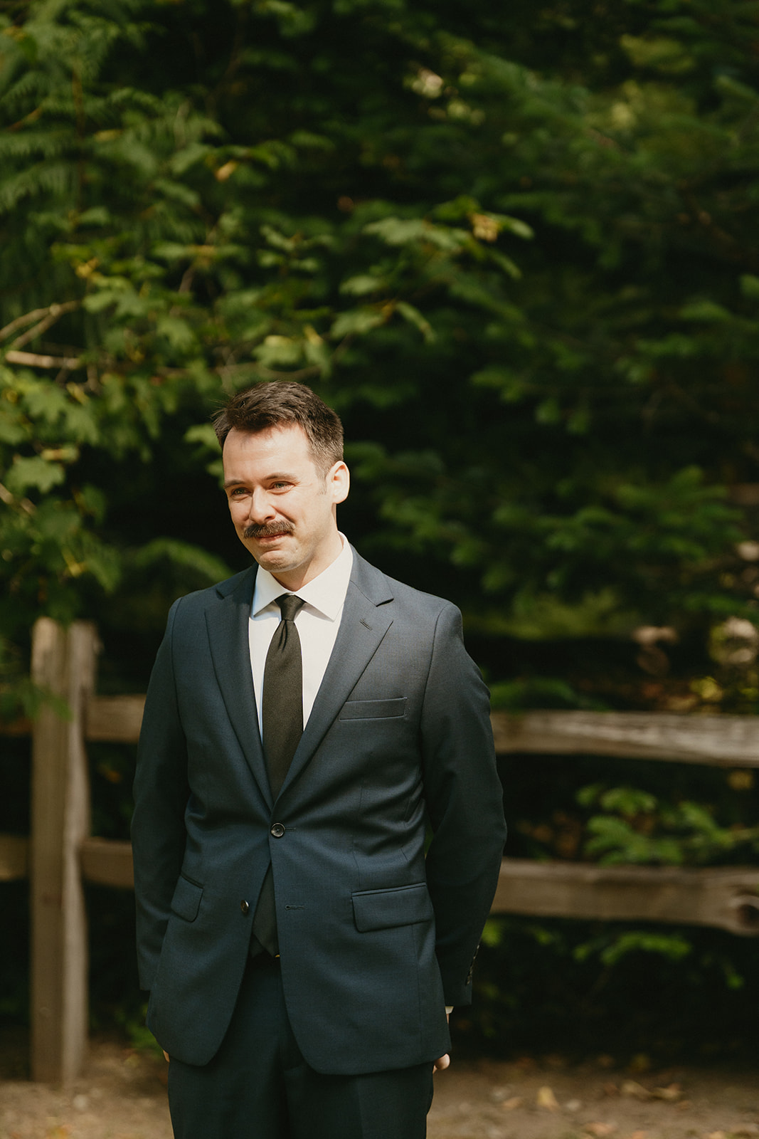 Portrait of the groom waiting before the first look, surrounded by forest.