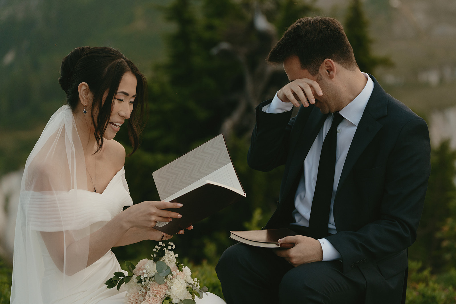 Groom wipes away a tear while the bride reads heartfelt vows during a quiet moment in the mountains.