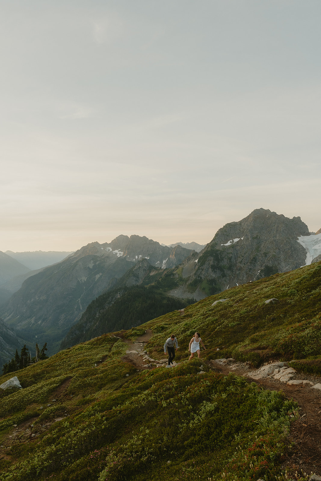 Wide shot of newly engaged couple walking along trail in washington mountains during outdoor engagement photos