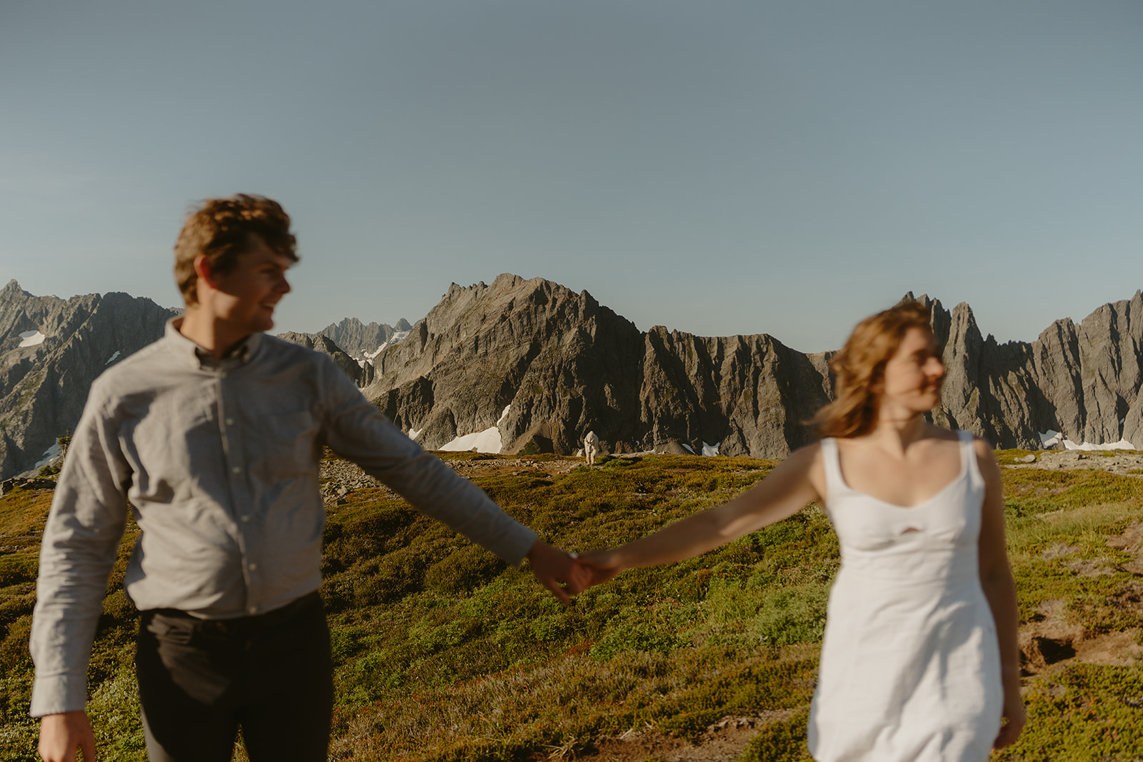 Couple holding hands while standing together in a scenic mountain landscape.