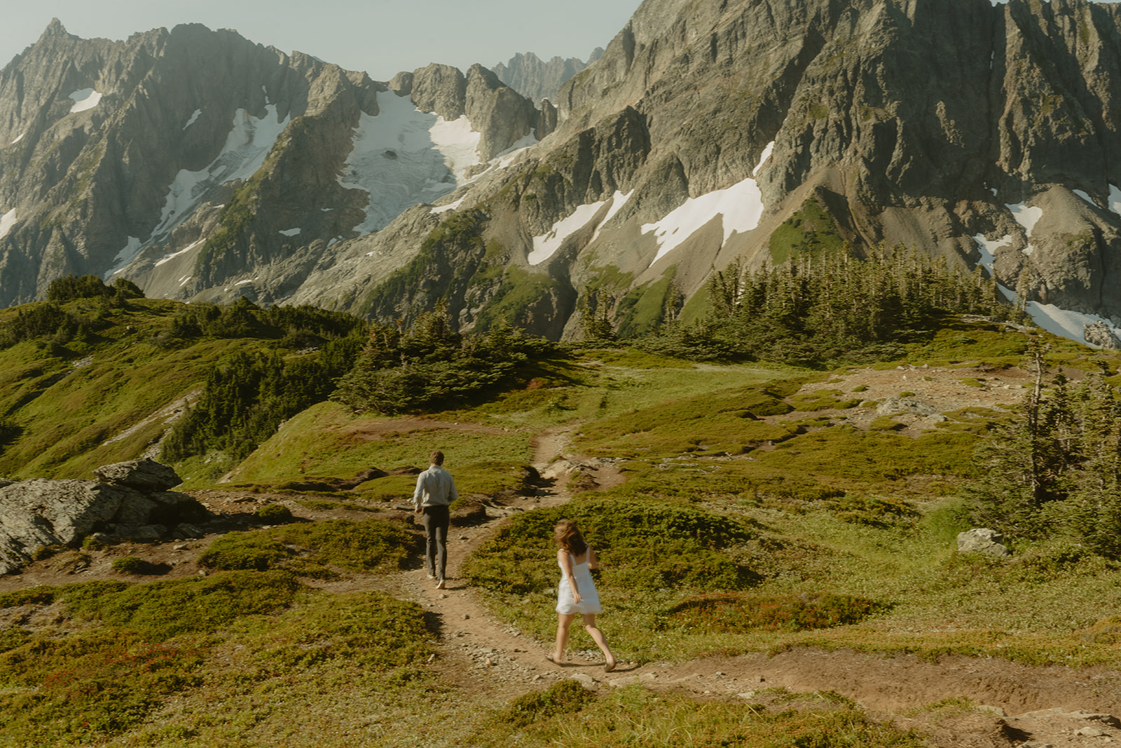 Couple walking through rocky trail in mountain range during outdoor engagement photos