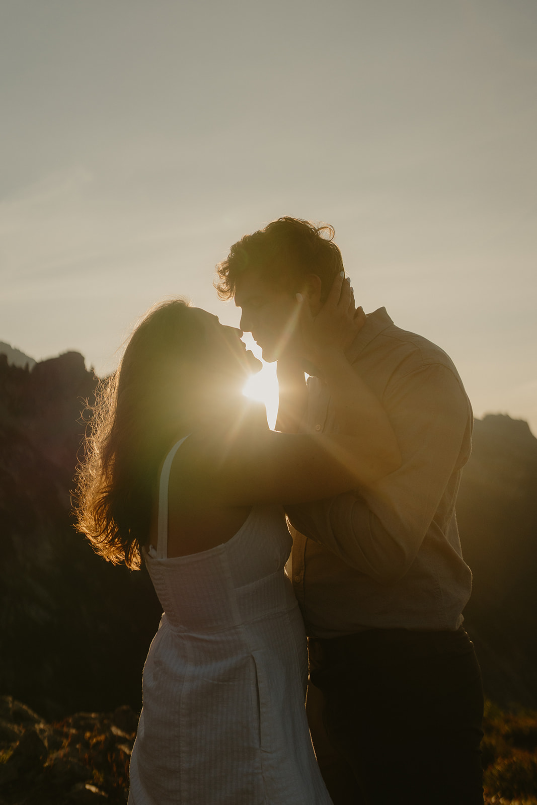 Couple embracing in a romantic moment about to kiss while sun flare is captured between them