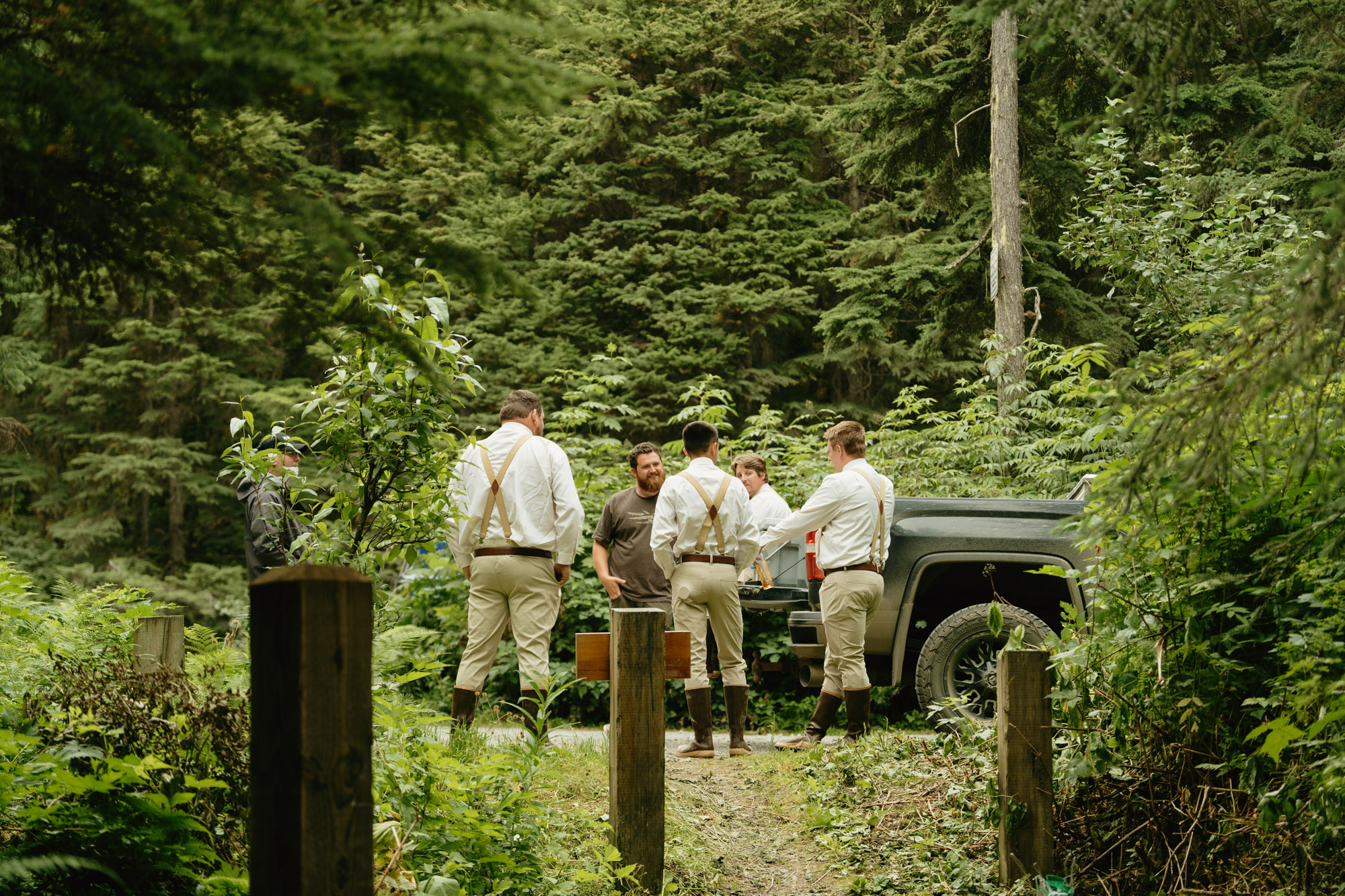 Groom and four groomsmen hanging out in the forest prior to the cermeony, sitting on the back of a pick up truck