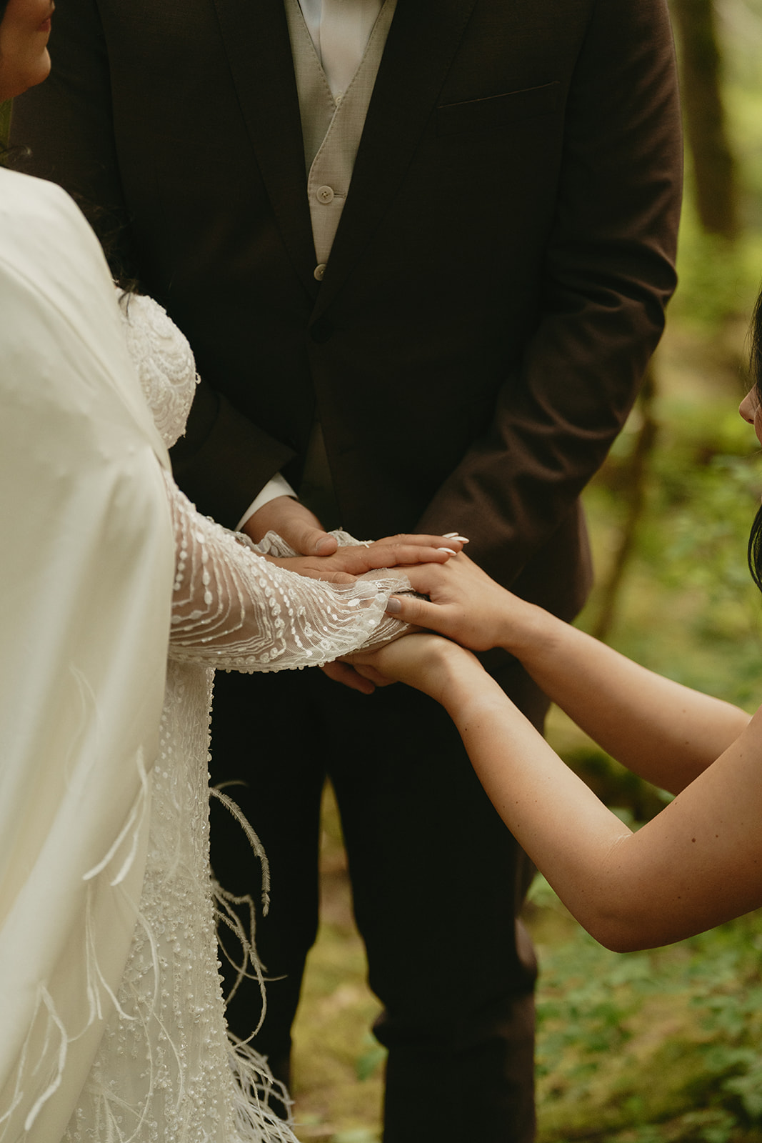 Couple shows wedding bands to friends and they all embrace and hold hands.