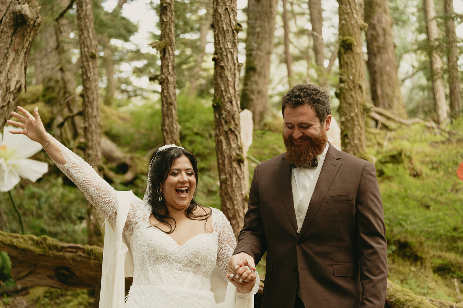 Bride throws her hands in the air in excitement after wedding ceremony is over.