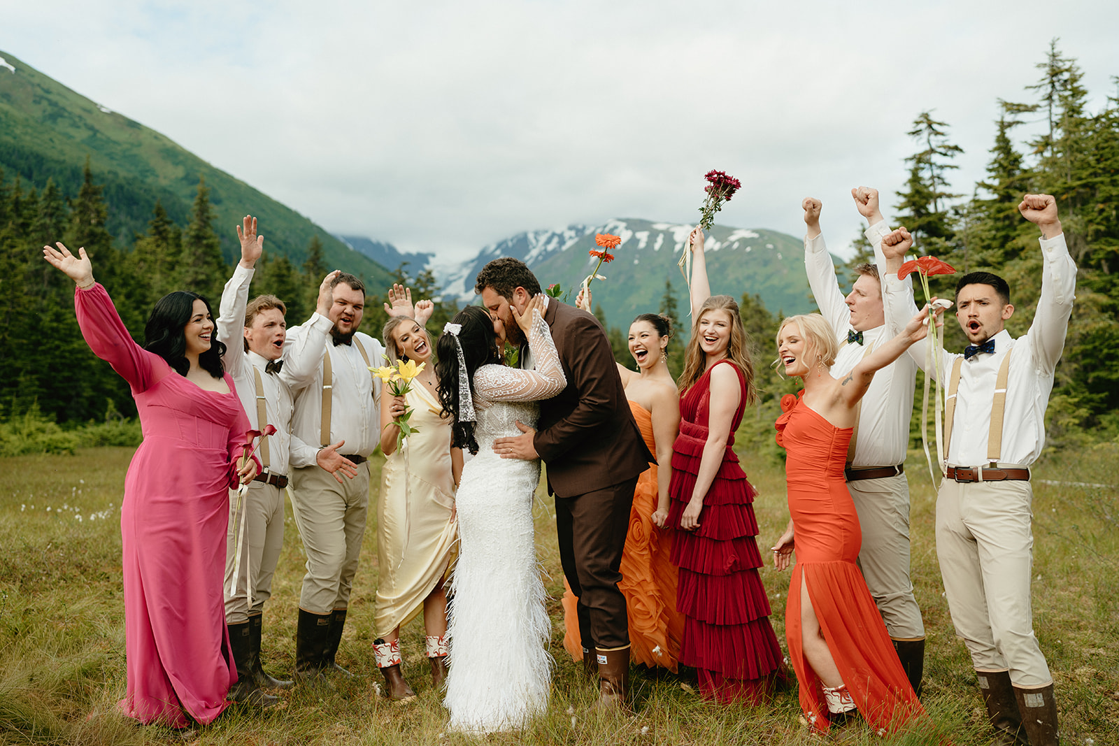 Bride and groom kiss as wedding party cheers behind them, celebrating their union and beautiful ceremony in Alaska