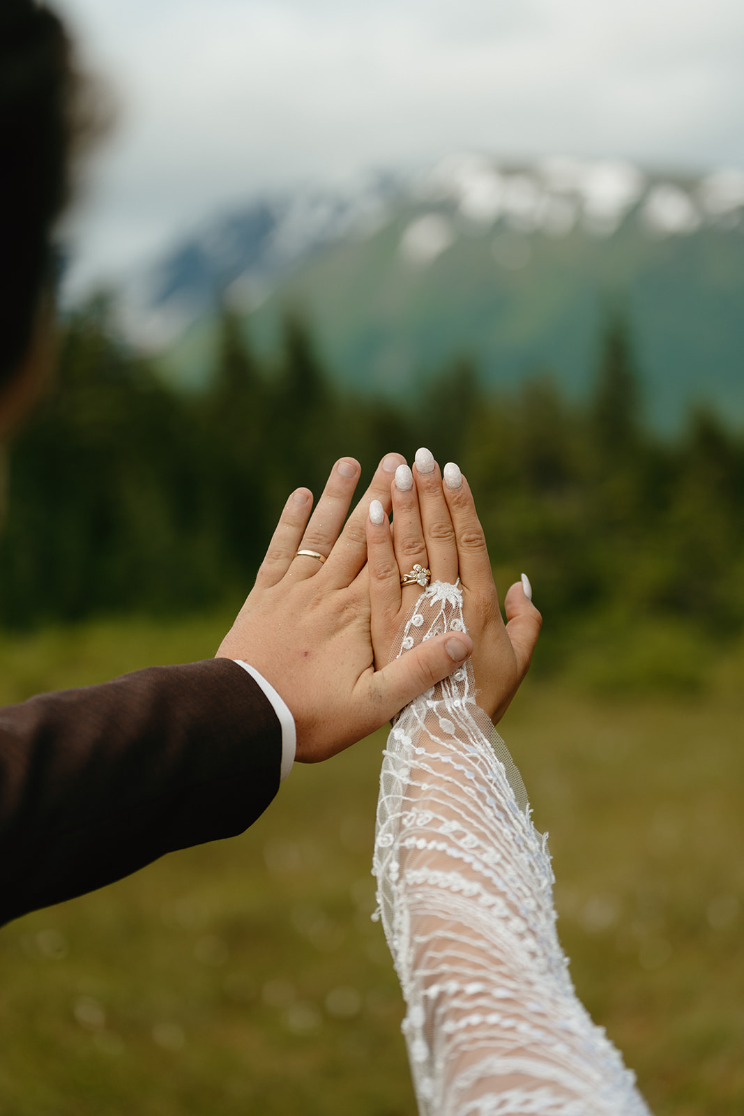 Couple holds hands up to show off new wedding bands after eloping to alaska